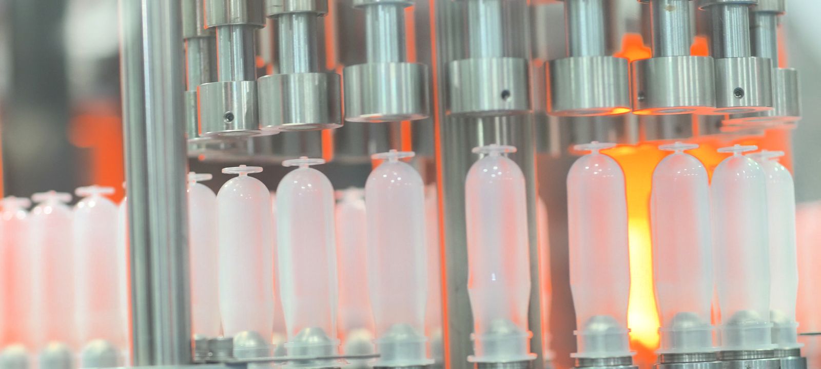 Polypropylene preforms glowing under the stretch rods of the blow-moulding machine